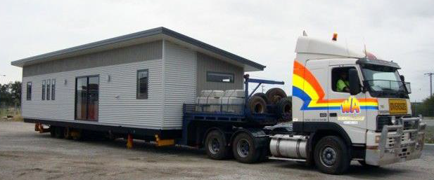 Image of a truck carrying a pre fabricated building.