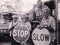 Historic black and white photo of workers holding road signs
