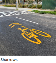 image of a yellow bicycle and chevron arrow painted on the road (a sharrow).