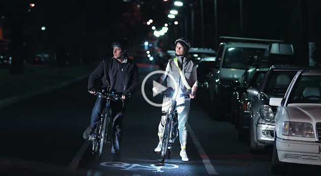 Two cyclists side by side on a bike path in the dark