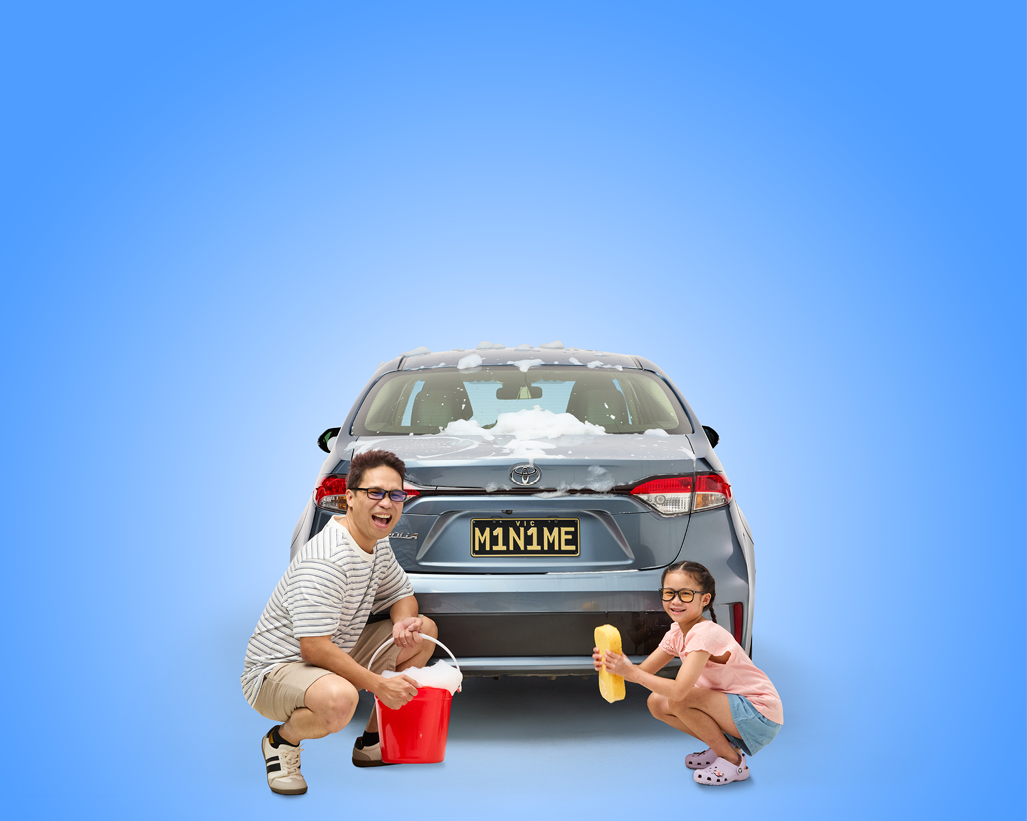 Woman with pug dog stands in front of blue car featuring the numberplate 'Puggly'.