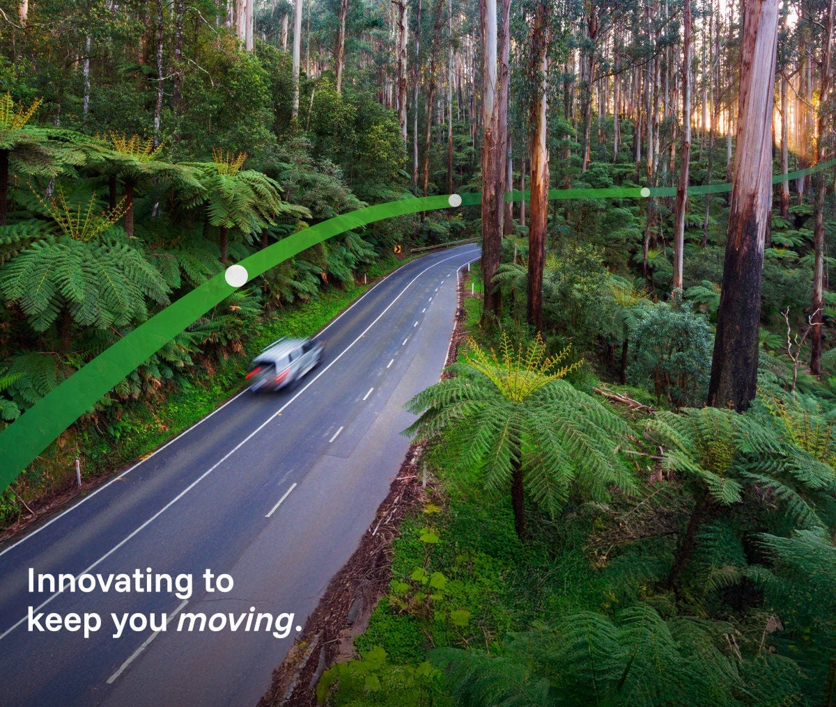 A white car drives through Victoria's Black Spur forest in the Yarra Ranges. The text 'Innovating to keep you moving' is displayed.