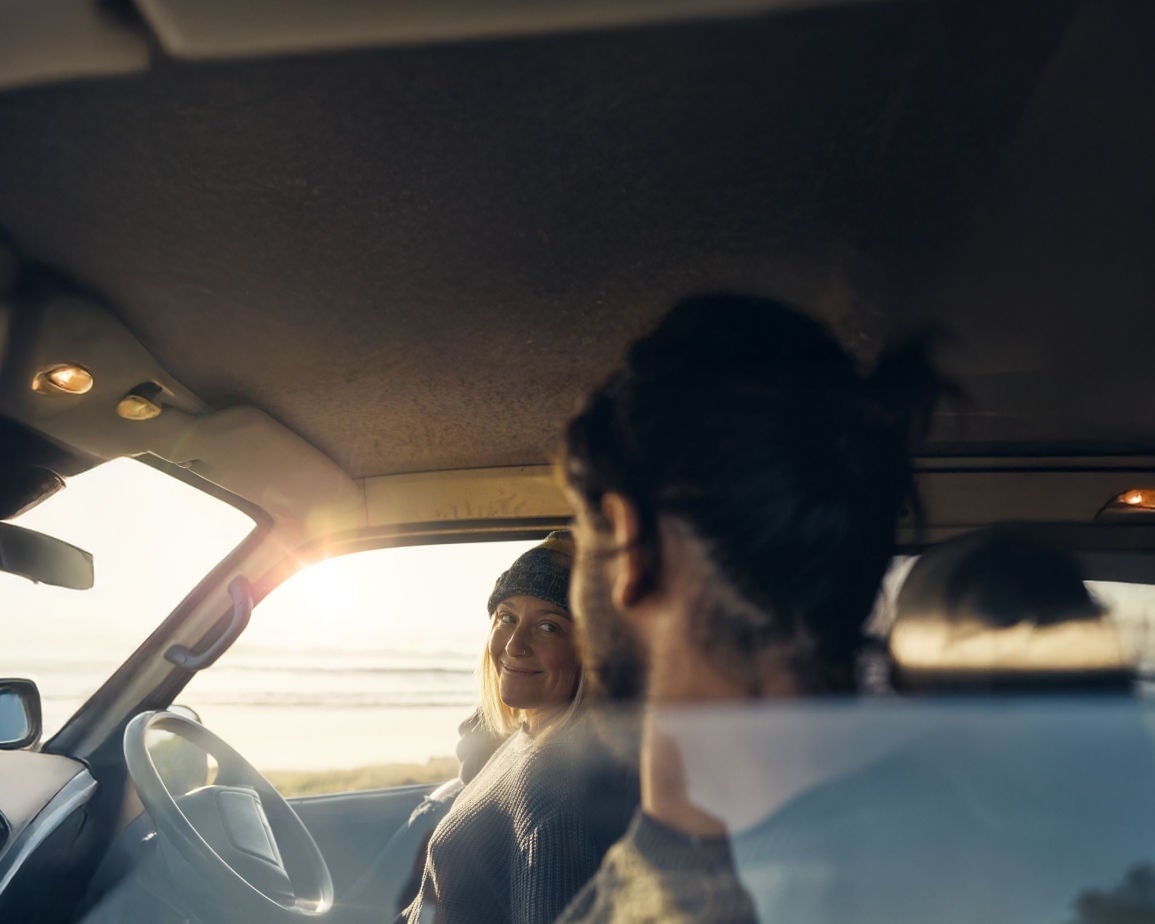 Couple inside a vehicle during a road trip near the coast. Find out how to pay your registration.