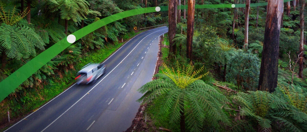 A white car drives through Victoria's Black Spur forest in the Yarra Ranges. The text 'Innovating to keep you moving' is displayed.