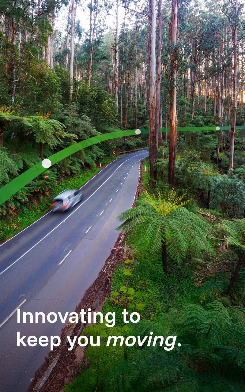 A white car drives through Victoria's Black Spur forest in the Yarra Ranges. The text 'Innovating to keep you moving' is displayed.