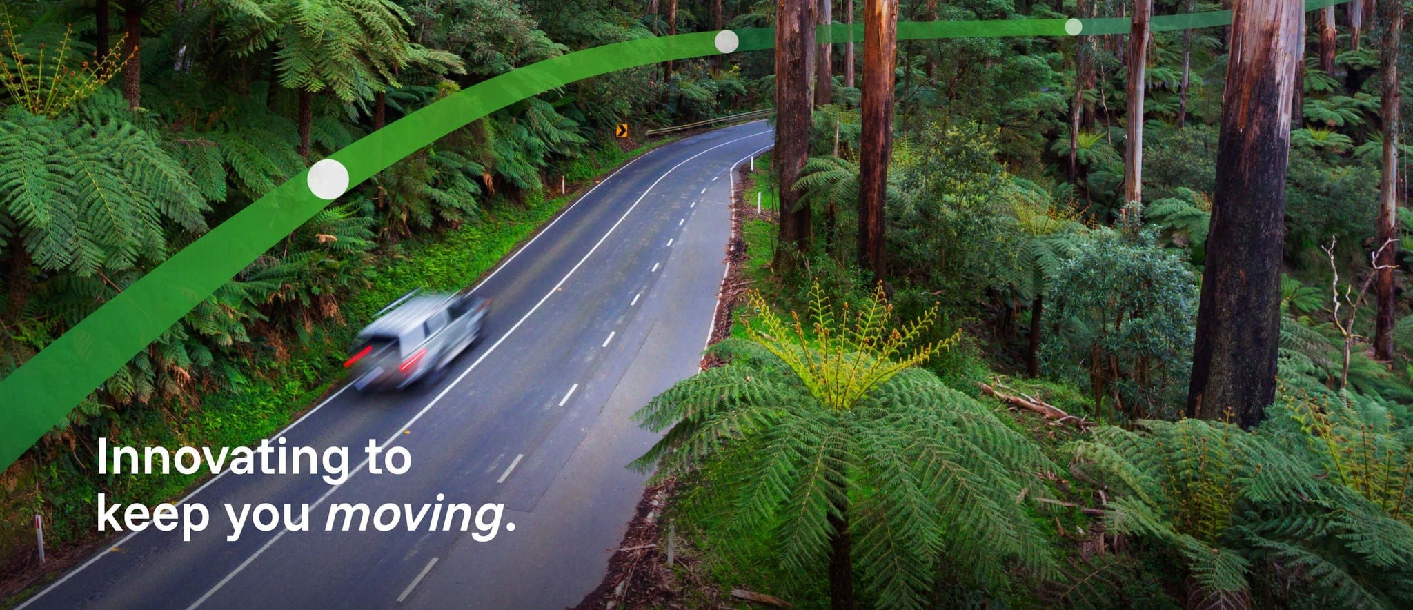 A white car drives through Victoria's Black Spur forest in the Yarra Ranges. The text 'Innovating to keep you moving' is displayed.