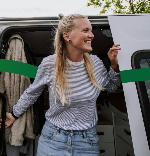 Woman steps out of a white van, holding on to the door while looking to the side.